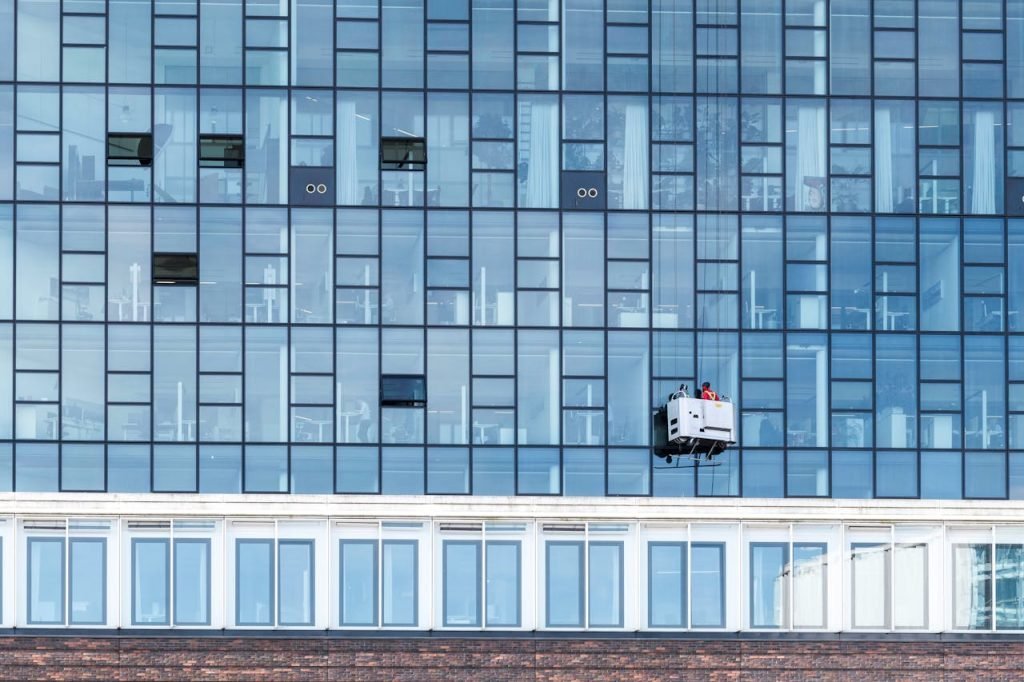 High-rise glass facade with cleaning platform and workers in Hamburg, Germany.
